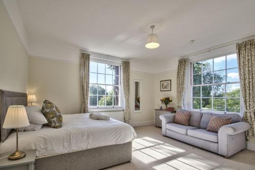 a bedroom with a bed and a couch and windows at Harkstead Hall By Group Retreats in Ipswich