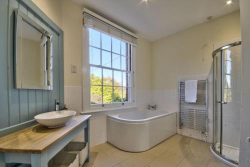 a bathroom with a tub and a sink and a bath tub at Harkstead Hall By Group Retreats in Ipswich