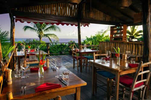 a restaurant with tables and chairs with the ocean in the background at Tet Rouge Resort in Soufrière