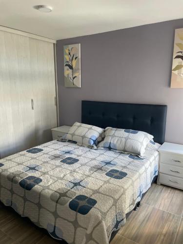 a bedroom with a bed with a blue and white quilt at Apartahotel in Ibagué