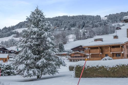 ムジェーヴにあるCharming flat with balcony at the foot of the slopes in Megève - Welkeysの山小屋前の雪に覆われたクリスマスツリー
