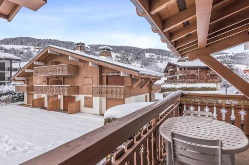 ムジェーヴにあるCharming flat with balcony at the foot of the slopes in Megève - Welkeysの雪に覆われた建物内にバルコニー(テーブル、椅子付)