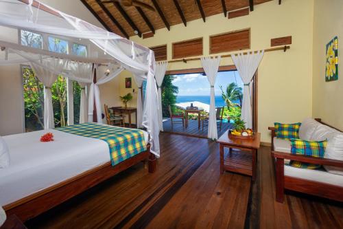 a bedroom with a bed and a view of the ocean at Tet Rouge Resort in Soufrière