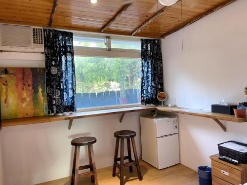 a kitchen with two bar stools and a window at 田中歐寒集b&b in Dongshan