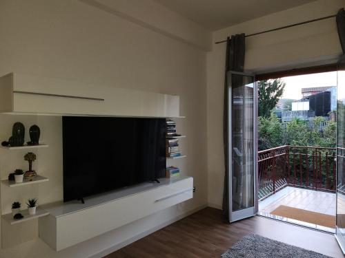a living room with a large television and a balcony at Appartamento Agrumi in Linguaglossa