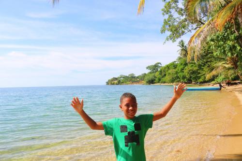 a boy standing on the beach with his arms in the air at Castillo Inspiracion Hostel in Bocas del Toro