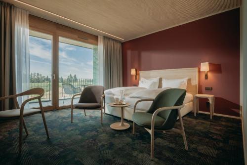 Habitación de hotel con cama, sillas y ventana en Landhotel Bohrerhof en Feldkirch