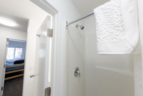 uma casa de banho branca com um chuveiro e uma toalha branca em UBC Okanagan Campus em Kelowna