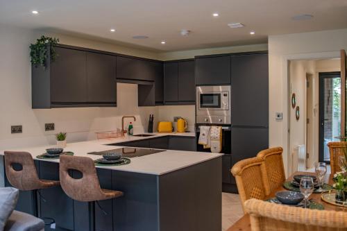 a kitchen with black cabinets and a table with chairs at BV Comfy Spacious 3 Bedroom TownHouse At One Cliff Oak Leeds Perfect For Contractors in Leeds