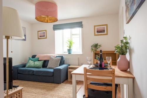 a living room with a blue couch and a table at Seashells, close to seafront, large private garden in Lyme Regis