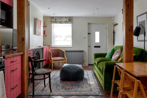 a living room with a green couch and a table at Pearls Cottage in Farnham