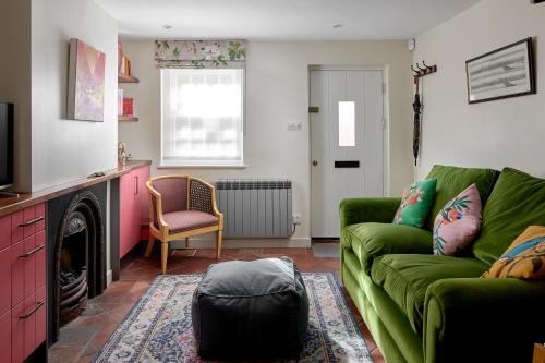 a living room with a green couch and a fireplace at Pearls Cottage in Farnham