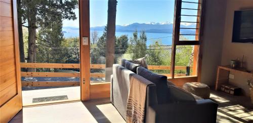 uma sala de estar com um sofá e uma grande janela em Casa Bosque em San Carlos de Bariloche