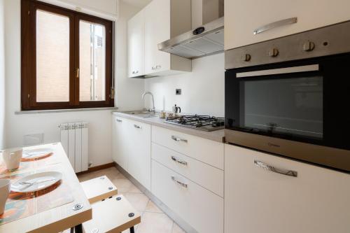 a kitchen with white cabinets and a flat screen tv at MIZAR- Appartamento privato con parcheggio gratuito by Appartamenti Petrucci in Foligno