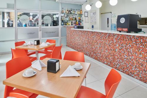 a restaurant with two tables and orange chairs and a counter at Best Western Plus Gran Hotel Centro Historico in Guadalajara