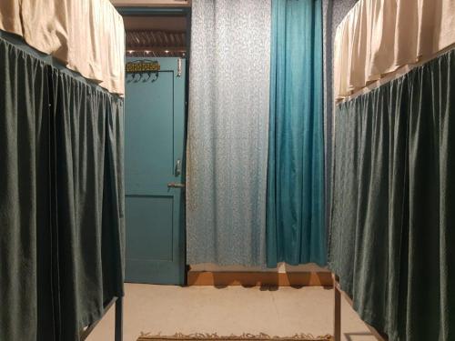 Zimmer mit blauen und grünen Vorhängen und einer Tür in der Unterkunft LA SIESTA INDIA MCLEODGANJ in McLeod Ganj