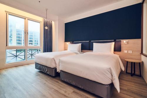 a hotel room with two beds and a large window at CHECK inn Select Taipei Nangang in Taipei