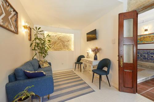 a living room with a blue couch and chairs and a desk at A Portuguesa Guest House in Porto