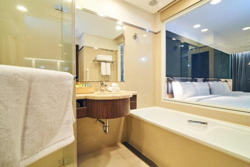 bagno con vasca e grande specchio di CHECK inn Select Taipei Nangang a Taipei
