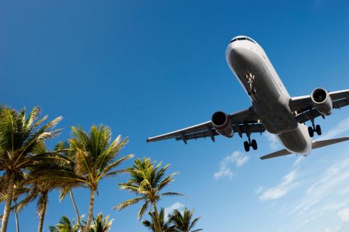 an airplane is flying over palm trees at American Inn Downey in Downey