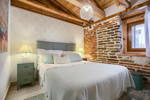1 dormitorio con cama y pared de ladrillo en AP Plaza de España 4, en Madrid