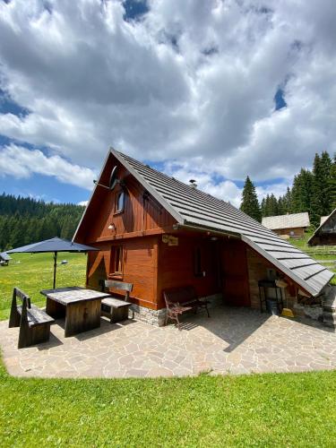 a small wooden cabin with a picnic table and a bench at Cosy Chalet on Pokljuka - Brunarica Tinkara in Zgornje Gorje