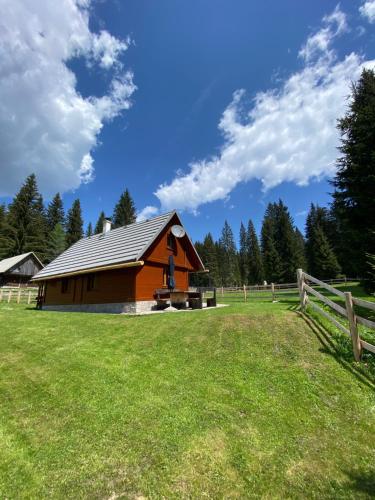 a barn in a field next to a fence at Cosy Chalet on Pokljuka - Brunarica Tinkara in Zgornje Gorje