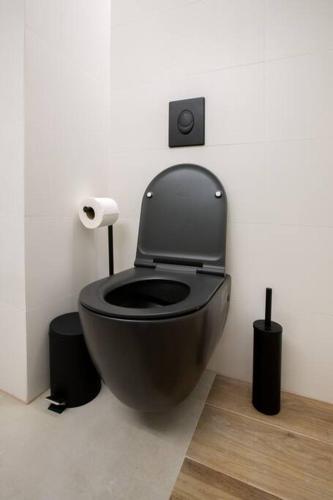 a bathroom with a black toilet in a room at Aphrodite Suite in Ashqelon