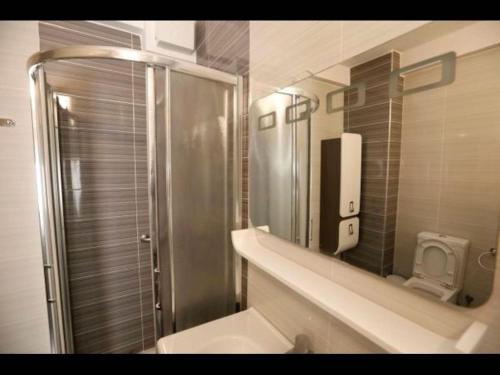 uma casa de banho com um chuveiro, um lavatório e um espelho. em Beachfront Sion Sarande Apartment 1 em Saranda