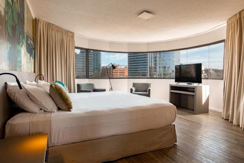 um quarto de hotel com uma cama grande e uma televisão em Palladium Business Hotel em Montevidéu