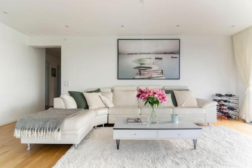 una sala de estar con un sofá blanco y un jarrón de flores en Penthouse with amazing views of Copenhagen!, en Copenhague
