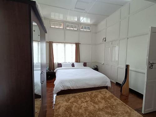 - une chambre avec un grand lit blanc et une fenêtre dans l'établissement Casa Encanto Homestay, à Shillong