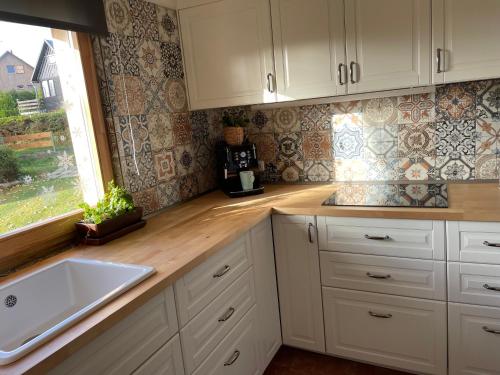 a kitchen with white cabinets and a sink and a window at Chata 1-Padesátka in Bedřichov