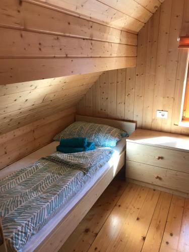 a bed in a cabin with a wooden wall at Cosy Chalet on Pokljuka - Brunarica Tinkara in Zgornje Gorje
