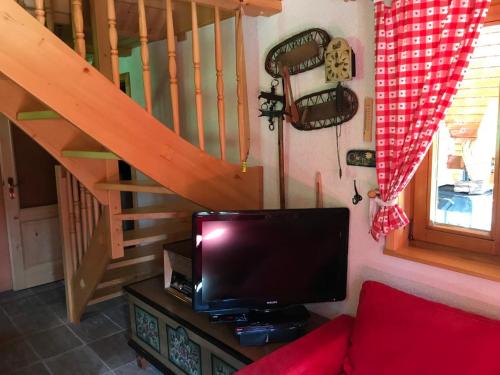 a living room with a tv and a staircase at Cosy Chalet on Pokljuka - Brunarica Tinkara in Zgornje Gorje