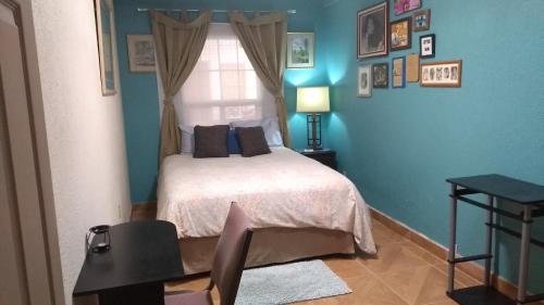 Dormitorio azul con cama y ventana en Loft Estudio El Faro - Zona Estero Beach, en Ensenada