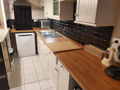 cocina con armarios blancos y encimera de madera en Ecully, appartement au calme de 50m²., en Écully