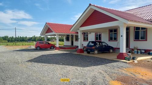 una casa con dos coches aparcados en un estacionamiento en Homestay Berkat D'sawah Tasek Berangan Pasir Mas, en Pasir Mas