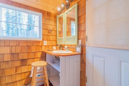 a bathroom with a sink and a window and a stool at Private Cabin With Alaskan Charm in Fairbanks