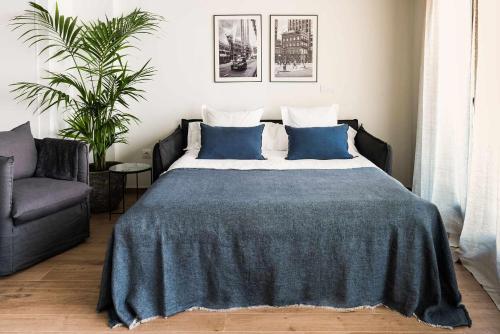 a bedroom with a bed with blue pillows and a chair at Apartamento Bguest con terraza in Alicante