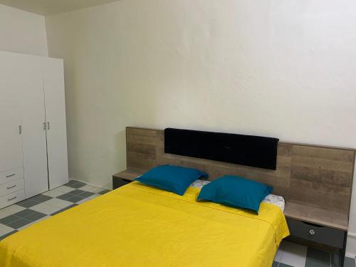 a bedroom with a yellow bed with two blue pillows at Appartement Orchidée 3 in Fort-de-France