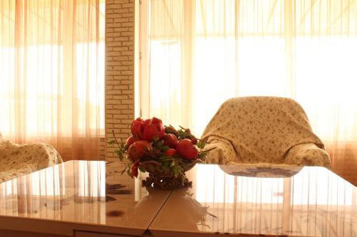 a glass table with a vase of red roses on it at Farmer's house in Vashlovani / ფერმერის სახლი ვაშლოვანში in Dedoplis Tskaro