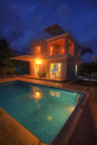 a house with a swimming pool at night at Villa Athina in Paphos