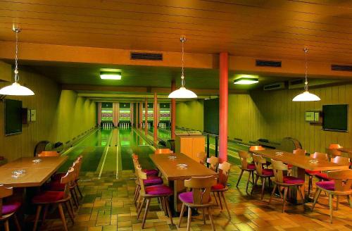 a restaurant with tables and chairs and a bowling alley at Hotel Elisabeth in Chienes