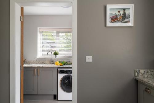 a kitchen with a sink and a washing machine at Arlyn, Padarn Lake Viewpoint in Snowdonia in Caernarfon