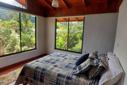 1 dormitorio con 1 cama y ventanas grandes en Juliet's Coffee House en Higueronal
