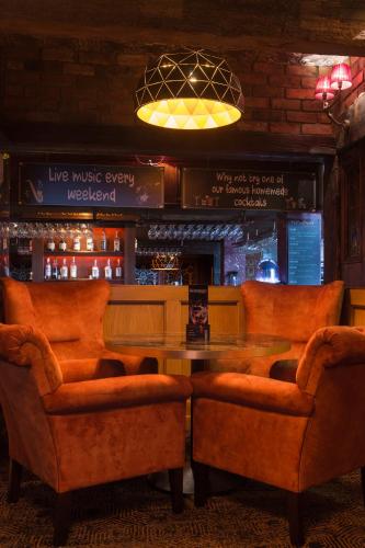 a bar with orange chairs and a table and a bar at Holyrood Hotel - Leisure Centre & The Spa at Orchids in Bundoran