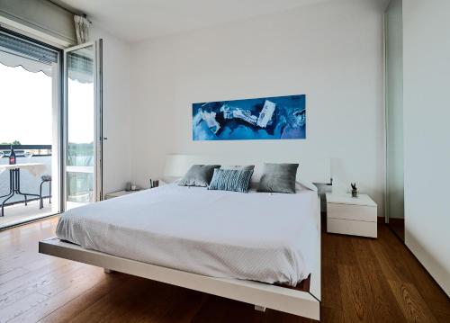 a white bedroom with a bed and a large window at San Siro Design Apartment in Milan