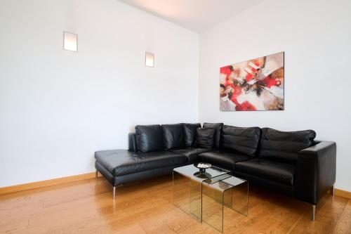 un sofá de cuero negro en una sala de estar con mesa en San Siro Design Apartment, en Milán