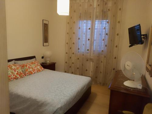 a bedroom with a bed and a window with a fan at BOLOGNA QUARTIERE SAVENA - APPARTAMENTO DI STEFANO in Bologna